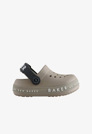Béžová gumová klumpa s čiernym nastaviteľným popruhom a ventilačnými otvormi. Obsahuje značku "BAKER by TED BAKER" v bielej farbe pozdĺž podrážky.