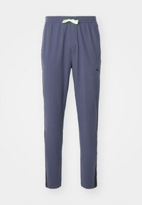 Marineblå sweatpants lavet af blødt materiale, med en elastisk talje og en lys grøn snor samt sorte detaljer på siden.