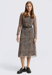 Robe midi à imprimé léopard avec manches longues transparentes, ceinture noire à la taille et ourlet festonné. Portée avec des chaussures noires épaisses.