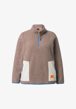 Pulower z polarowego materiału w kolorze taupe z niebieskim suwakiem w połowie długości oraz kremowymi kontrastowymi kieszeniami z zamkami błyskawicznymi i pomarańczową łatą.