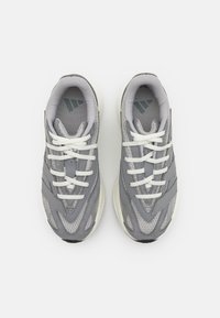 Gray athletic shoes with a mesh and leather upper, featuring white laces, textured accents, and a rubber sole.