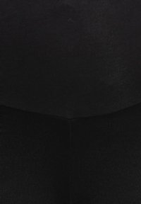 Leggings pretos feitos de tecido canelado, apresentando um ajuste justo e um design sem costuras. A textura é suave, com costuras visíveis mínimas.