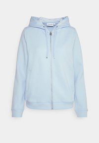 Ljusblå hoodie tillverkad av mjukt tyg, med en framzipper, dragsko i huvan och sidofickor. Enkel, minimalistisk design.