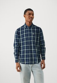 Donkerblauw en groen geruite button-up overhemd met lange mouwen en een borstzak. Gemaakt van een zachte, gestructureerde stof.