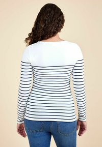 Stribet langærmet skjorte i hvid og marineblå, der har et tætsiddende design med rund halsudskæring og blød, glat tekstur.