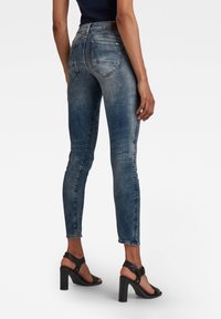Dunne blauwe jeans met een vervaagd design, vijf zakken en een medium taille. Draag ik met zwarte hoge hakken.