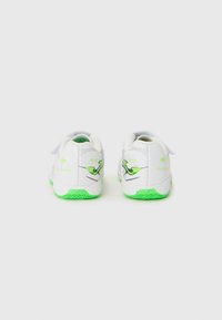 Scarpe da ginnastica bianche con suola verde, design elegante, cinturino in Velcro e branding minimalista sul tallone e sui lati.