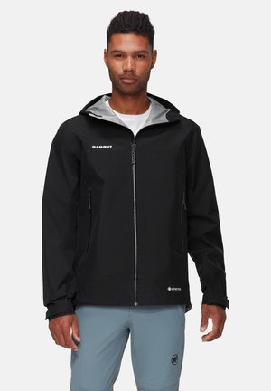 Veste noire imperméable avec une doublure intérieure grise, fermeture éclair frontale et poches zippées. Présente le logo Mammut et la marque GORE-TEX.