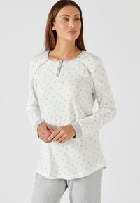 Light gray pajama top with small floral patterns, long sleeves, a wide neckline, and three buttons at the collar; paired with gray pants.