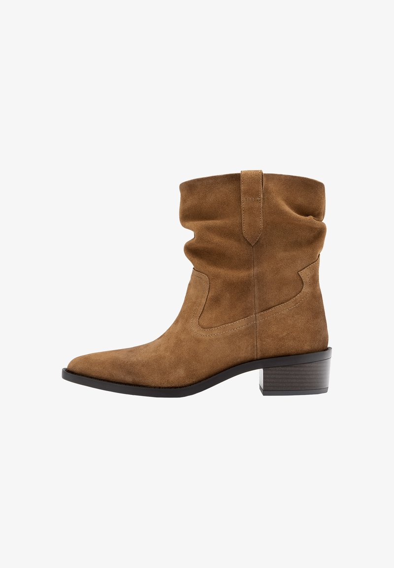 Brązowy zamszowy kozaki do połowy łydki z luźną cholewką, szpiczastym noskiem, pętelką do zakładania i niskim, warstwowym obcasem na białym tle.