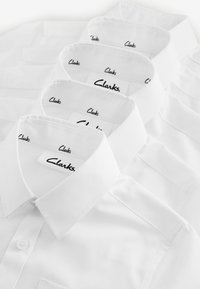 Witte overhemden met knoopsluiting, een gladde textuur en subtiele branding met "Clarks" op de binnenlabels.