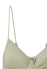 Jasnooliwkowy stanik z cienkimi regulowanymi ramiączkami, w dekolcie w kształcie litery V oraz gładkiej fakturze. Posiada centralny detal w postaci węzła oraz subtelne wzory.