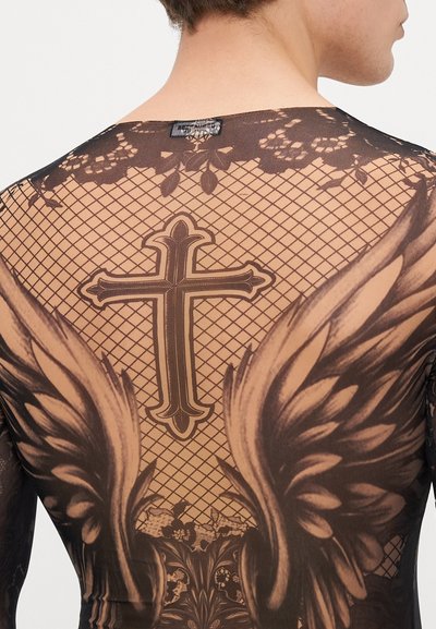 Top nero trasparente con un design a rete, dotato di ali stampate e una croce centrale sul retro, che mette in evidenza intricati modelli floreali.