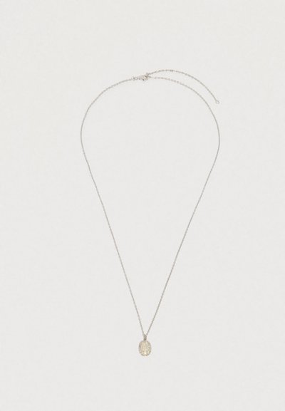 Λεπτό ασημένιο κολιέ αλυσίδας με ένα μικρό οβάλ μενταγιόν, επενδυμένο με μικρά λαμπερά κρυστάλλινα στοιχεία σε απλό ανοιχτό φόντο.