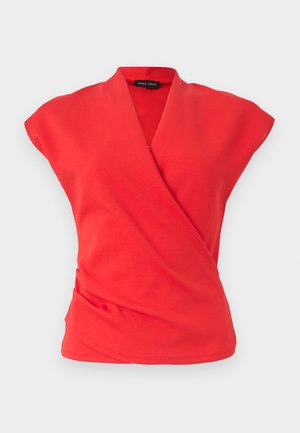 Κόκκινο αμάνικο τοπ σε στυλ τύλιγμα με V λαιμόκοψη και ελαφρώς μαζεμένο ύφασμα στη μέση, απεικονισμένο σε απλό φωτεινό φόντο.