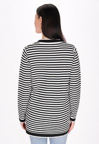 Pasiasta koszula z długim rękawem w czarno-białe wzory, z okrągłym dekoltem i kontrastowym czarnym wykończeniem. Miękki materiał o luźnym kroju.