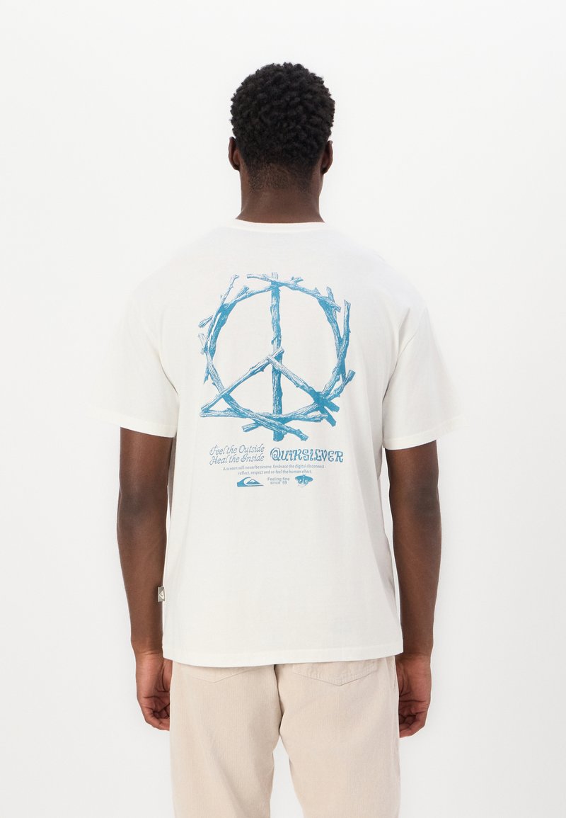 Weisses Baumwoll-T-Shirt mit einem blauen Friedenszeichen aus Zweigen auf der Rückseite, versehen mit blauem Text und einem kleinen Etikett an der Seitennaht.