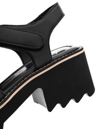 Black leather platform sandal with a thick, serrated sole and an ankle strap featuring hook-and-loop closure.