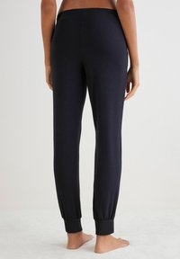 Zwarte, slim-fitting jogpants met een elastische tailleband en nauwsluitende boorden, gemaakt van zachte stof, met een gladde, lichte textuur.
