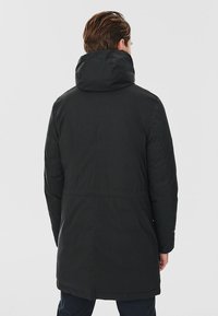 Czarny park z wysokim kołnierzem i kapturem, o gładkim, matowym wykończeniu oraz nieco dłuższym tylnym końcu, zapewniającym dodatkową osłonę.