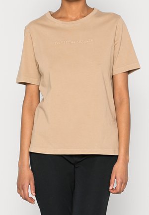 Beige katoenen T-shirt met korte mouwen en een ronde hals. Voorzien van een geborduurd "TOMMY HILFIGER" logo op de borst.