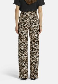 Weite Hosen aus einem hellbraunen Stoff mit einem auffälligen Leopardenmuster in Schwarz und Braun. Glatte Textur mit einem elastischen Bund für optimalen Tragekomfort.