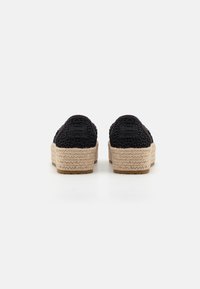 Zapatos de encaje negro con suelas de plataforma de yute trenzado y suelos de goma, con forma redondeada y talón elevado para mayor soporte.
