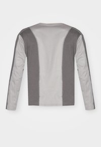 Long-sleeve shirt in gray with contrasting light gray side panels. Soft fabric with a crew neckline and stitched detailing along the seams.