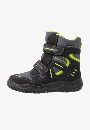 Czarno-szary dziecięcy zimowy but z limonkowo zielonymi akcentami, dwoma paskami na rzep oraz grubą, fakturowaną podeszwą, oznaczony napisami "superfit" i "GORE-TEX".