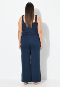 Námořnický dvoudílný outfit obsahující přiléhavý top s širokými ramínky a volné kalhoty s širokými nohavicemi. Měkká tkanina s hladkým povrchem.