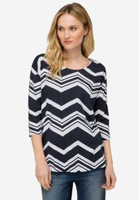 Námořnický a bílý top s ševronovým vzorem, tříčtvrteční rukávy, kulatý výstřih a volný střih. Měkká tkanina s hladkým povrchem.
