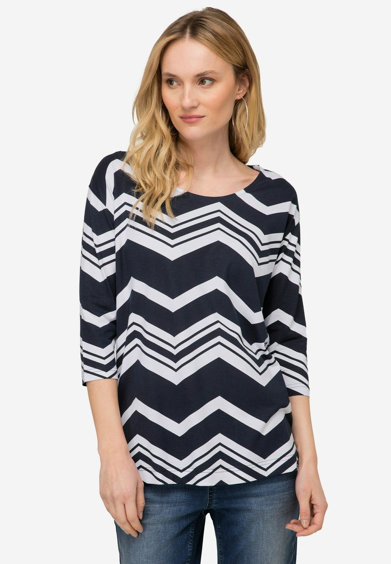Námořnický a bílý top s ševronovým vzorem, tříčtvrteční rukávy, kulatý výstřih a volný střih. Měkká tkanina s hladkým povrchem.