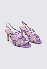 Sandalias de satén moradas con tacones, tiras entrecruzadas, punta abierta y correa ajustable en el tobillo. Presenta un elegante tacón de aguja.