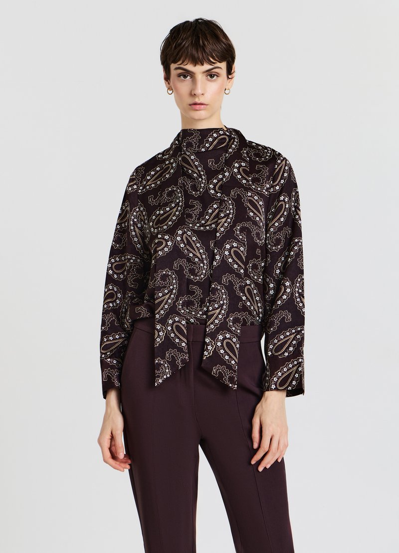 Dunkel gemusterte Bluse mit Paisleymuster und hohemkragen, mit vorderem Knoten. Aus glattem Stoff gefertigt, hat sie lange Ärmel und eine lockere Passform.