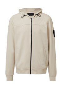 Felpa beige con zip, cappuccio regolabile con coulisse, due tasche laterali, polsini a coste e una piccola toppa nera di stoffa sulla manica. Texture liscia.