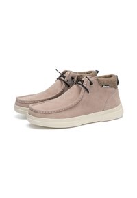 Bottines en daim marron clair avec des semelles en caoutchouc beige, des lacets noirs et une doublure en laine visible autour du col. Détails de couture simples inclus.