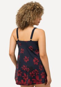 Robe de bain florale en marine, ornée de fleurs rouges. Bretelles ajustables et coupe ample, fabriquée en tissu léger avec une texture lisse.