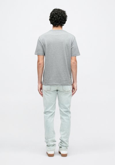 Γκρι βαμβακερό μπλουζάκι με κοντά μανίκια και στρογγυλή λαιμόκοψη, συνδυασμένο με ανοιχτό μπλε τζιν παντελόνι, με ορατές ραφές και casual γραμμή.