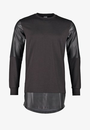 Čierna mikina s koženými rukávmi a dlhším, lesklým čiernym lemom. Má okrúhly výstrih a voľný strih. Celková hladká textúra.