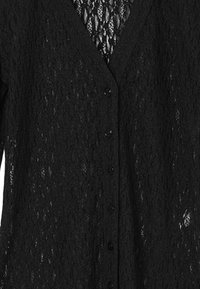 Schwarze Spitzenstrickjacke mit V-Ausschnitt, Knopfverschluss und einem strukturierten Muster, das das halbtransparente Material betont.
