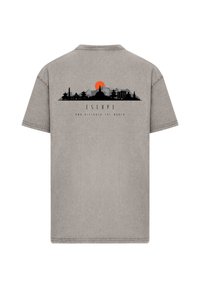 Gray t-shirt featuring a black skyline design with an orange sun, and text "ESCAPE AND DISCOVER THE WORLD" below the image. Short sleeves.