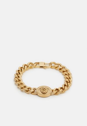 Bracelet chaîne ton or avec un médaillon rond présentant une tête de lion au centre et une fermeture sécurisée.