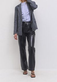 Szary w kratkę marynarka, niebieska koszula w paski, czarne szerokie spodnie z sztucznej skóry i czarne sandały na paski. Strukturalny design z widocznymi szwami.