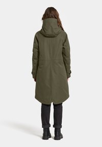 Olivegrön, mellanhängig kappa med huva, knäppta manschetter och kjol med utsvängd kant. Tillverkad av ett slätt, vattentåligt material.