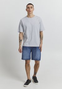 Gray cotton t-shirt with a relaxed fit, paired with blue denim shorts. Black sneakers complete the outfit. Minimalistic design and no visible patterns.