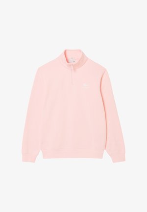 Pullover rosa chiaro con colletto alto e zip a metà. Realizzato in tessuto morbido, presenta un piccolo logo bianco Lacoste sul petto. Maniche lunghe.
