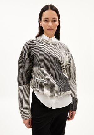 Textured knit sweater in black and white stripes, featuring a relaxed fit, round neckline, and contrasting angular patterns on sleeves.