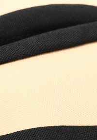 Material textil de culoare bej, cu un overlay negru proeminent. Suprafața pare netedă, cu o textură fină și fără modele sau accesorii vizibile.
