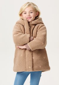 Beige Fleece-Mantel mit Kapuze, oversized Form und gerippten Bündchen. Verfügt über dekorative orangefarbene Punktakzente und eine weiche Textur.