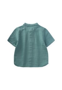 Camicia a maniche corte in tessuto teal opaco, con colletto, finitura testurizzata e orlo curvo. La vista posteriore mostra un dettaglio a cappio.